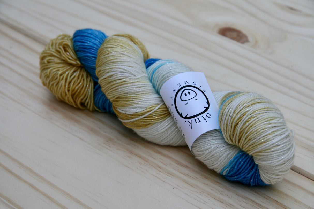 A single twist of yarn rests on a wooden background.