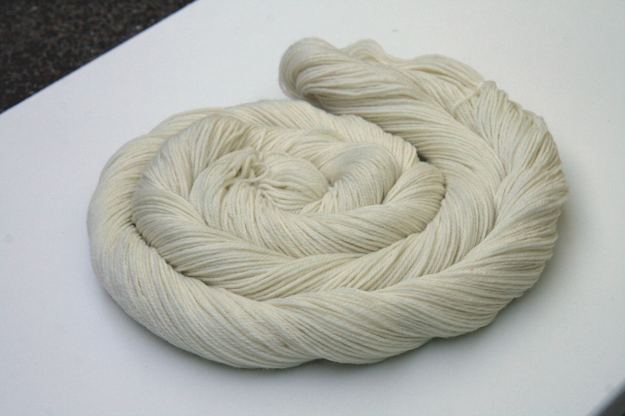 A swirl of pale cream yarn rests on a clean white background.
