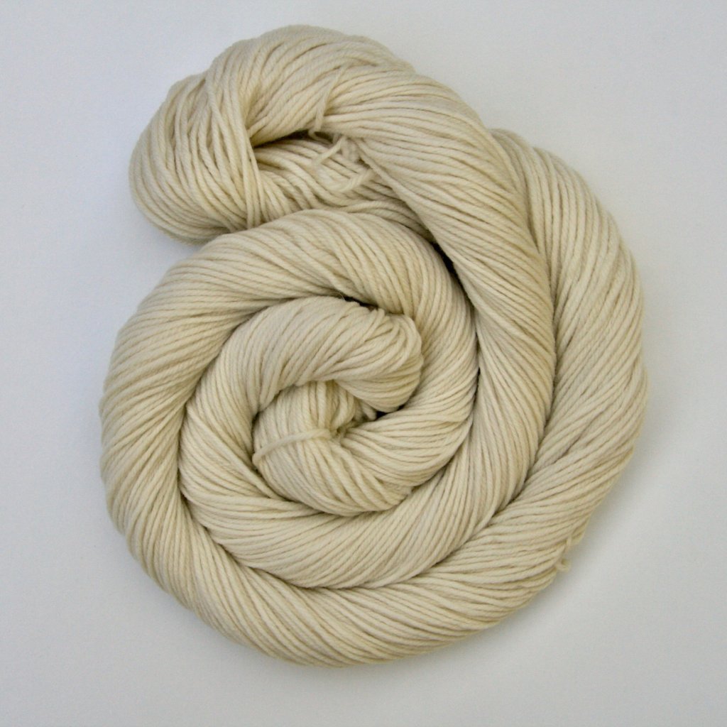 A curl of undyed yarn resting on a crisp white background.