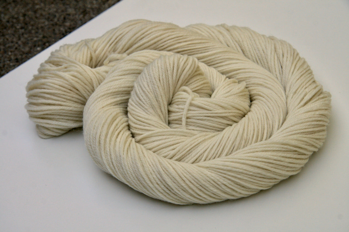 A swirl of pale cream yarn rests on a clean white background.