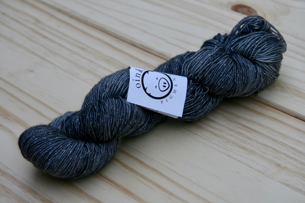 A richly colored twist of yarn rests on a wooden background.