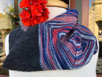 A close up of a multi-color cowl rests on the neck of a body form.