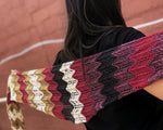 A multicolored shawlette is held across the back of a person in a black shirt facing away from the camera.
