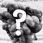 a black and white image of a pile of yarn on small slatted stool, with a white question mark in the middle