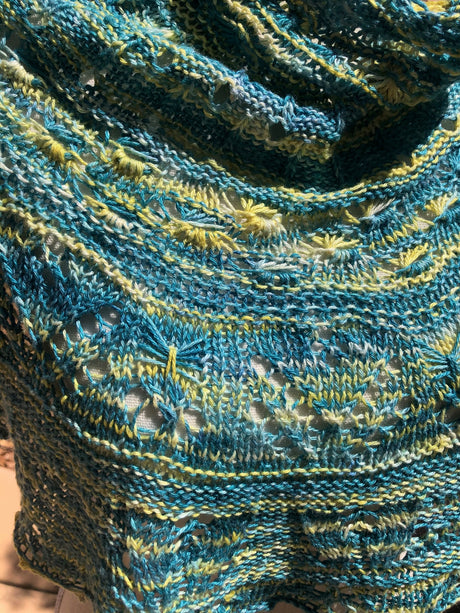 A close up of a lacy cowlette against a white body form.