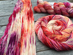 A panoply of yarn in various stages of being hanked rests on a wooden table top.