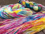 Three skeins of yarn in various stages of being skeined up rest on a wooden background. 