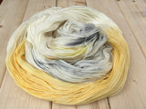 An untwisted skein rests in a lush pile atop a light wooden background. 