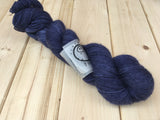 A single skein of yarn rests on a light wooden background.