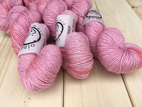 Three skeins of yarn snuggle against a light wooden background. 