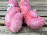 two brightly colored skeins rest against a grey wooden background. 
