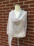 A lovely lacy wrap is draped artfully around a torso mannequin against a brick background. 