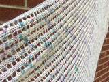 A close up shot of a lacy wrap against a brick wall. 