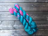 two brightly colored skeins rest against a dark wooden background. 