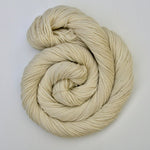 A swirl of pale cream yarn rests on a clean white background. 