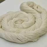 A close up shot of a cream swirl of yarn rests against a clean white background. 