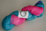 a plump skein of intense pink and rich teal yarn rests on a clean white background. 