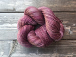A circular donut of yummy plum-purple yarn rests on a wooden background.