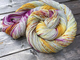A bright swirl of yarn curls around itself like a labyrinth against a grey wooden background. 