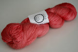 a single skein of almost luminous yarn rests on a plain white background. A small white label can be seen on the skein.