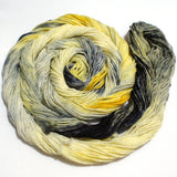 A swirling round of lemon yellow and inky black yarn rests against a clean white background. 