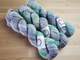 Three skeins snuggle together on a light wooden background.