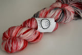 a bright red twist of yarn rests on a white background. 