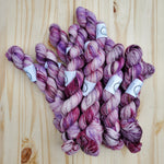 A bundle of purples and pinks rest on a light wooden background. 