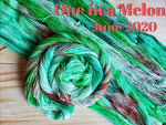 several skeins of yarn laid out with 1 twisted into a spiral all skeins are bright green with a splash of deeper bright green and coral with black speckles, text in coral reads "One in a Melon June 2020"