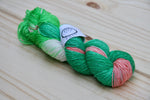 A richly colored twist of yarn rests on a wooden background. 