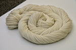 A swirl of pale cream yarn rests on a clean white background. 