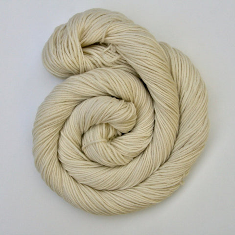 A curl of undyed yarn resting on a crisp white background. 
